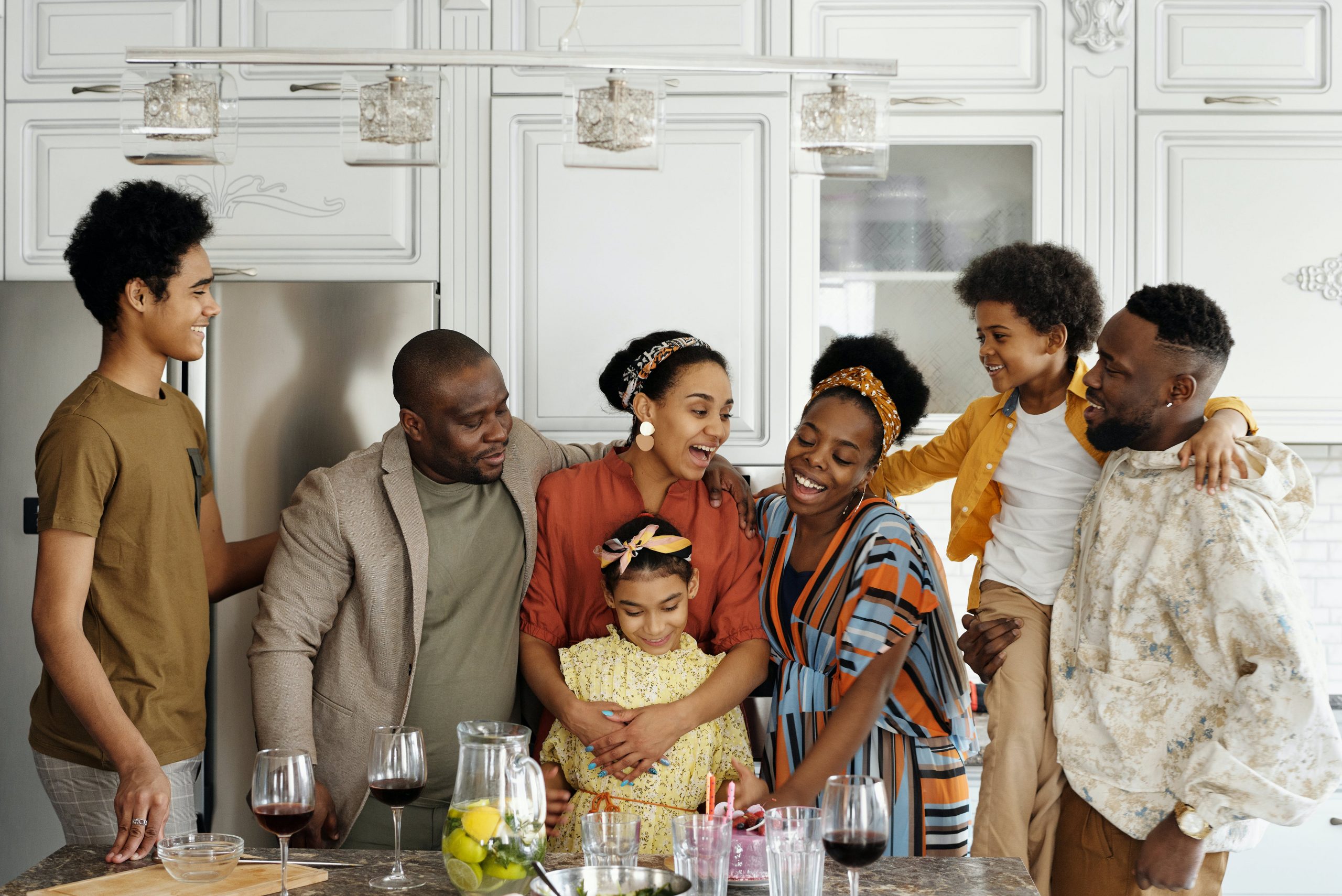 A joyful multi-generational family gathered together in a cozy kitchen, smiling and embracing. 
