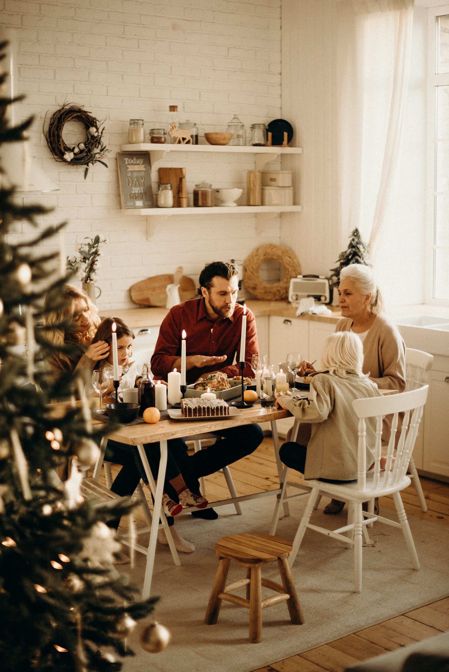 Family enjoying a festive meal together in a warmly lit kitchen with Christmas decor. 