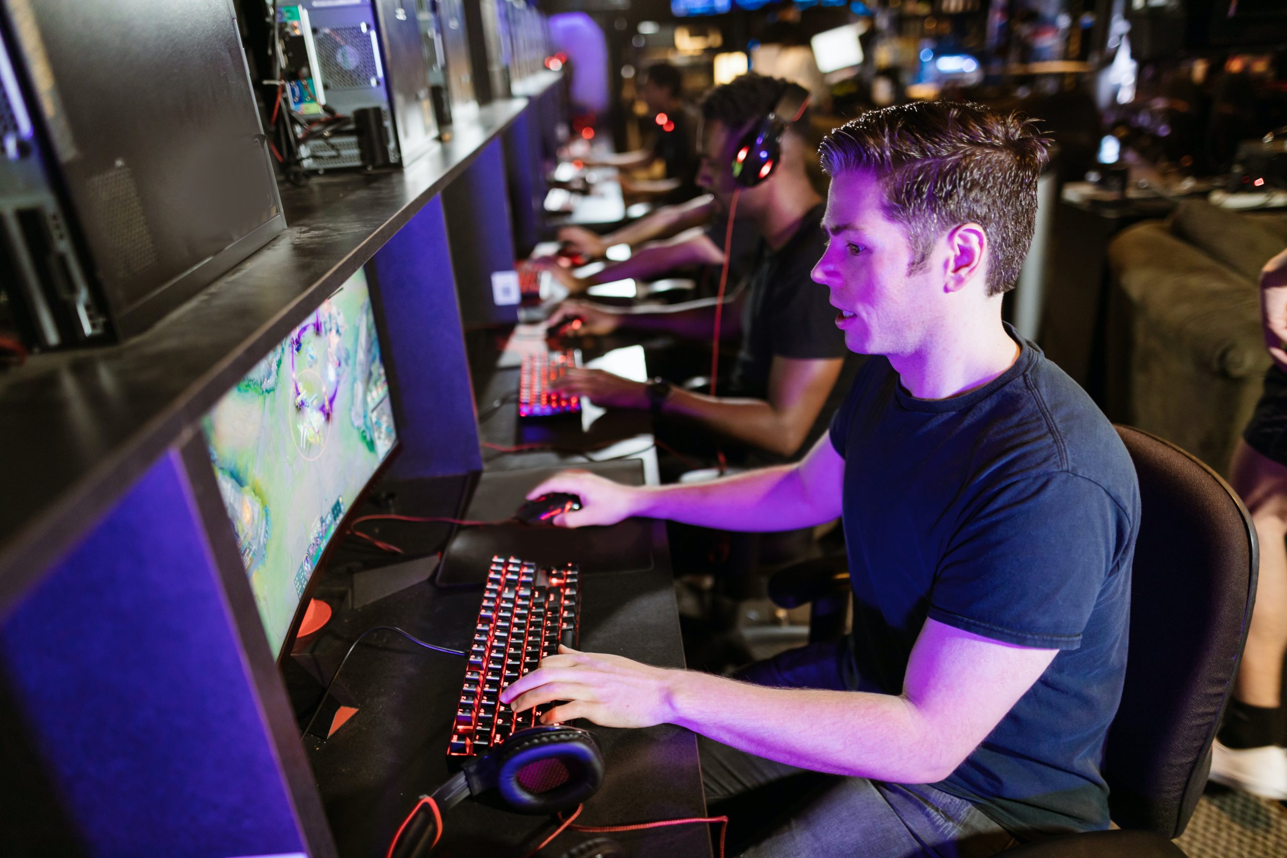 Focused individuals at a gaming center intensely playing video games on high-performance PCs. 