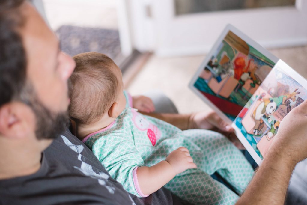 Father reading a book with his 3 year old child not talking but understands