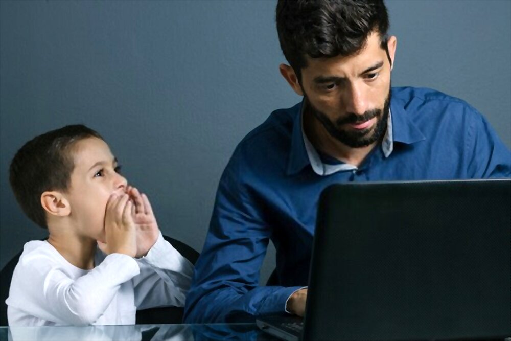 Father working on laptop, ignoring his son 