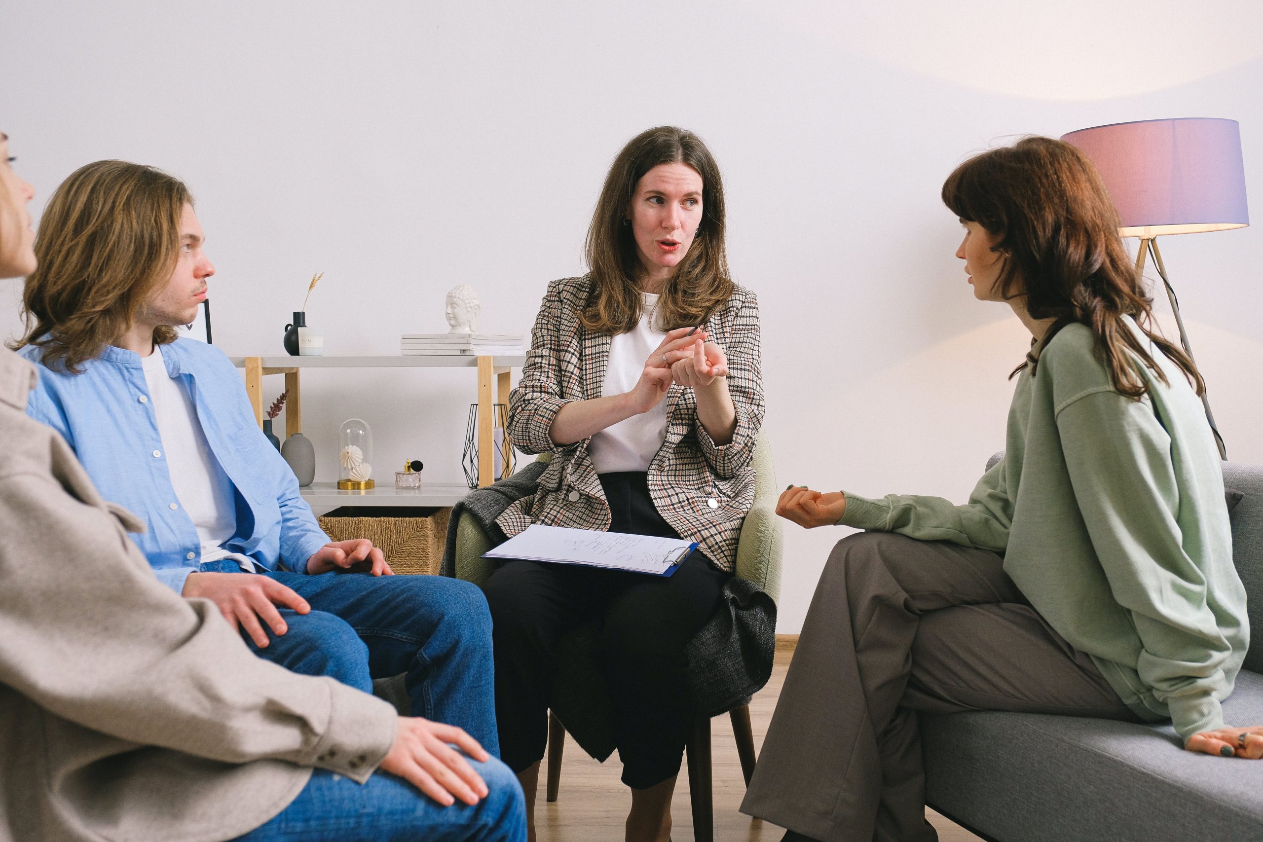 A therapist discussing with a couple and their son in a session, with attentive expressions.