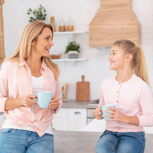 Mother and daughter are enjoying drinking coffee together.